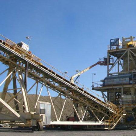 Industrial conveyor belt system with machinery against a clear blue sky